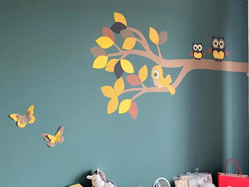 Warme groene babykamer met een okergele uilentak behangsticker
